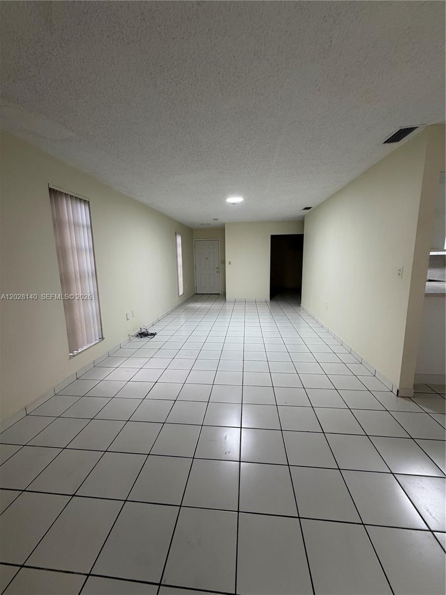 A long, narrow room features white tiled floors, light-colored walls, and a white ceiling — MIAMI, FL