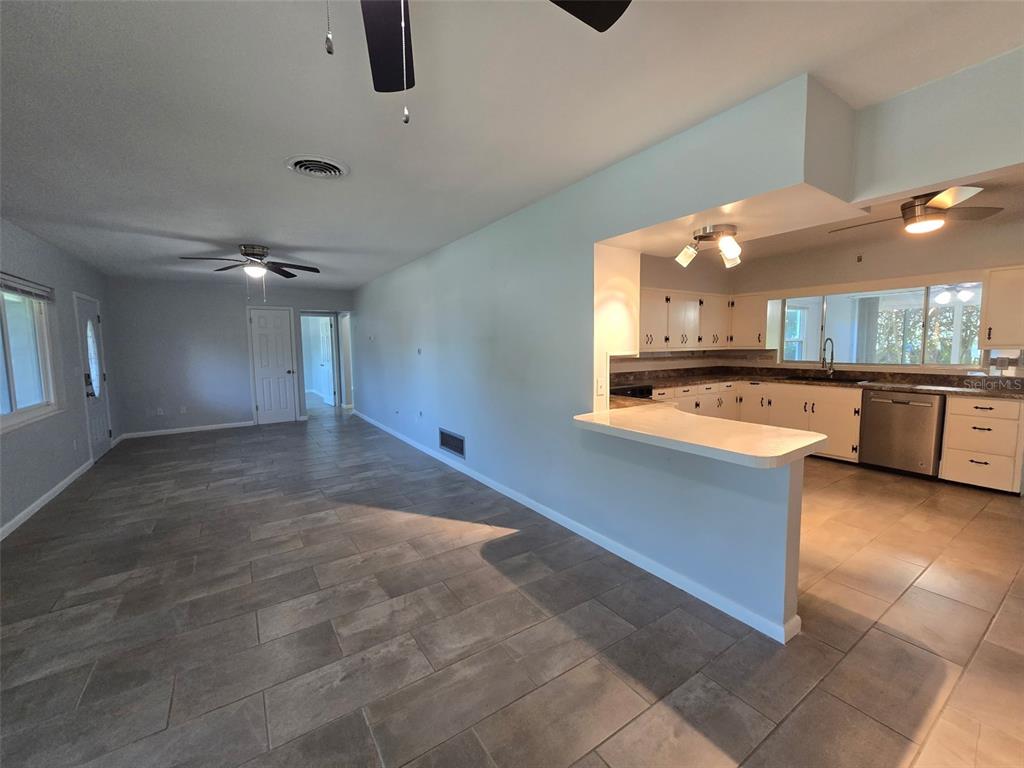 A view of a living room with tile floors leading into a kitchen with white cabinets — 507 LAKE LULU DRIVE, WINTER HAVEN, FL