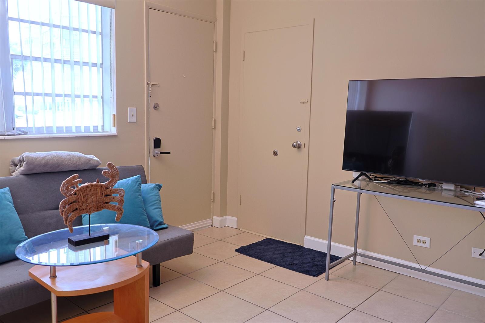 A living room features a gray sofa, glass coffee table, television on a stand, and tile — 26 Diplomat Parkway # 2280, FL 33009, FL