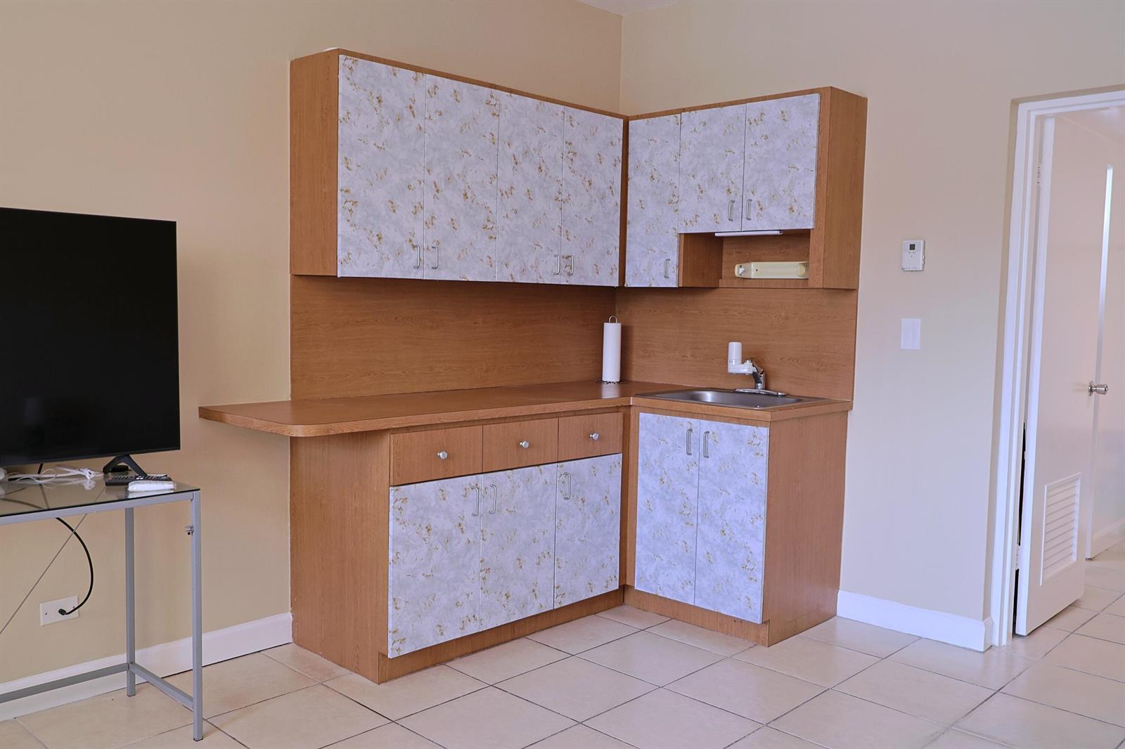 A small kitchenette features light wood cabinets with patterned doors and a stainless steel sink — 26 Diplomat Parkway # 2280, FL 33009, FL