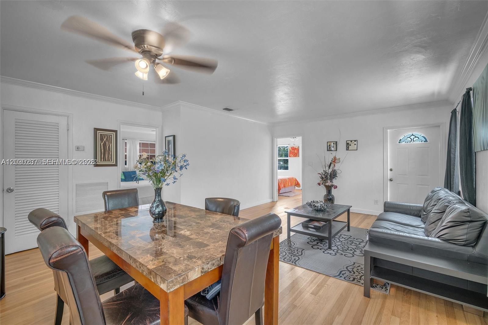 A dining area with a marble-top table sits adjacent to a living room with hardwood floors — 1635 Hollywood Blvd # A, Hollywood FL 33020, HOLLYWOOD, FL