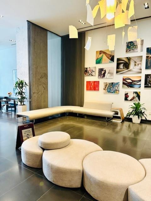 A modern lobby features a curved sectional sofa, circular ottomans, and wall-mounted artwork — 1600 NE 1 # 1915, Miami FL 33132, MIAMI, FL