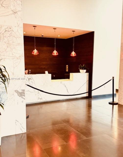 A marble reception desk sits in front of a dark wood wall with three pendant lights — 1600 NE 1 # 1915, Miami FL 33132, MIAMI, FL