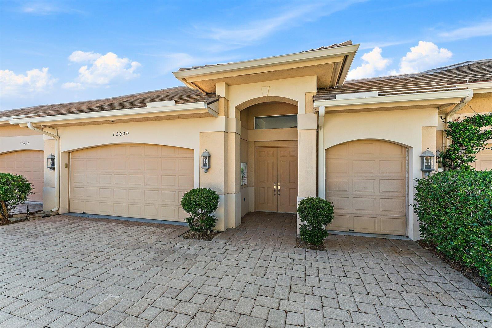 A beige stucco building features two garage doors and a central double-door entryway — 12020 SE Birkdale Run, Jupiter FL 33469, JUPITER, FL