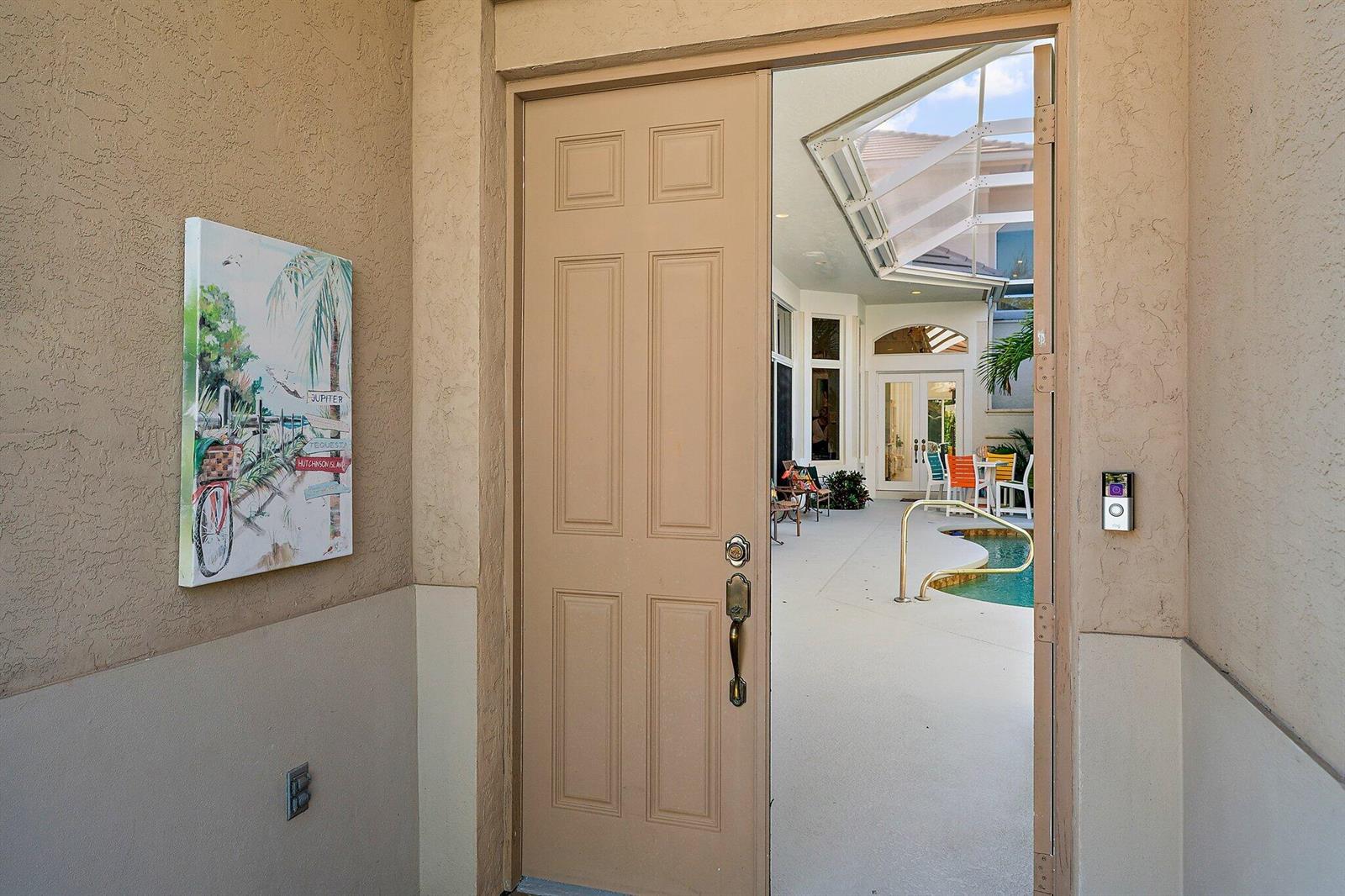 A tan front door opens to a screened-in patio with a pool and outdoor seating — 12020 SE Birkdale Run, Jupiter FL 33469, JUPITER, FL