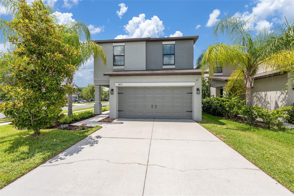 A kitchen with wood cabinets, granite countertops, and a white sink overlooks a dining area — 7423 CLARY SAGE AVENUE, TAMPA, FL