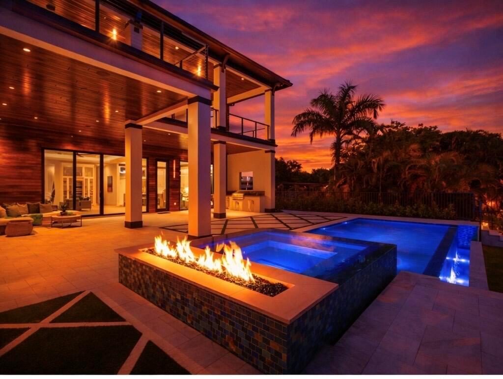 A modern house exterior features a fire pit, a glowing pool, and a sunset sky — 736 Lagoon Drive, North Palm Beach FL 33408, NORTH PALM BEACH, FL