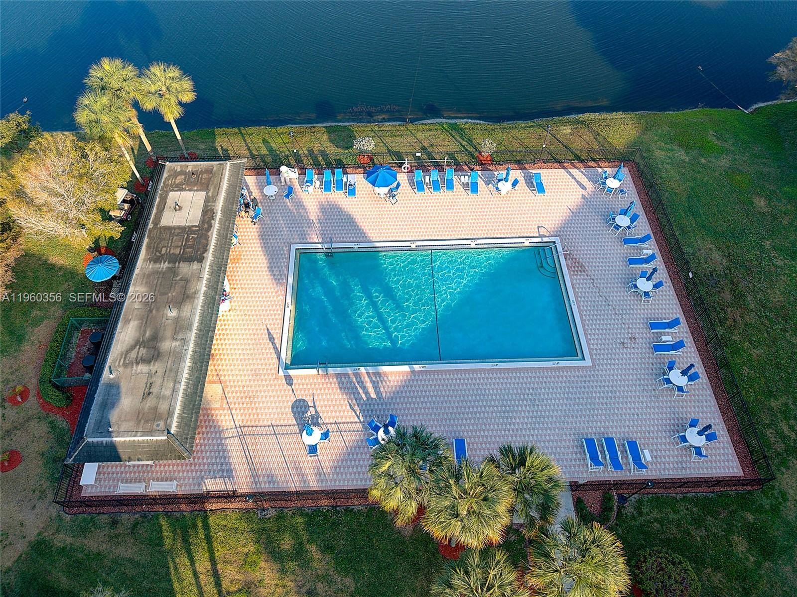 An aerial view shows a rectangular swimming pool surrounded by a patio, lounge chairs, and landscaping — 1803 Eleuthera Pt # G4, Coconut Creek FL 33066, COCONUT CREEK, FL