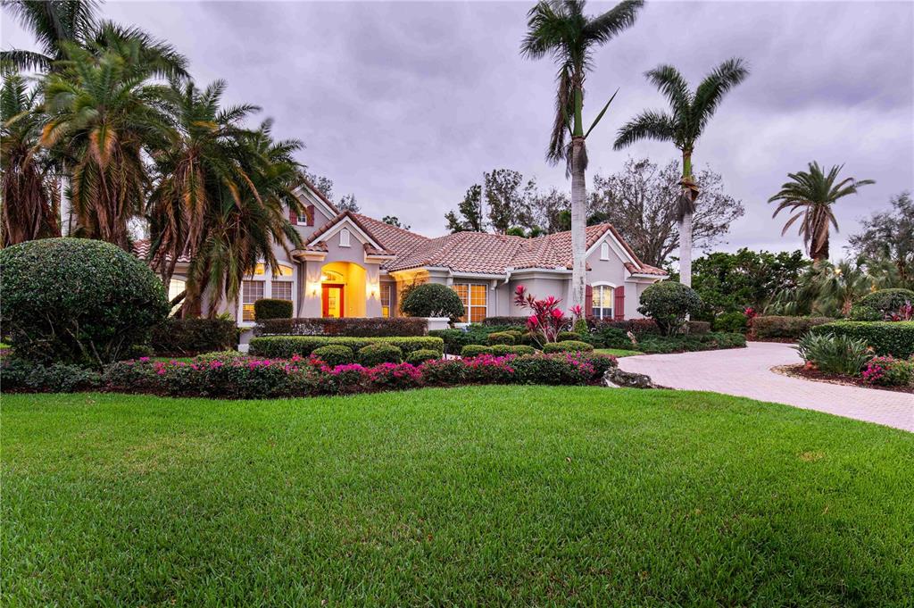 A single-story house with a tile roof, palm trees, and a landscaped front yard — 10006 DISCOVERY TERRACE, BRADENTON, FL