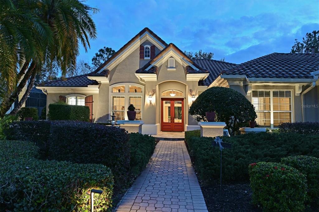 A single-story house with a tiled roof, red double front doors, and a paved walkway — 10006 DISCOVERY TERRACE, BRADENTON, FL