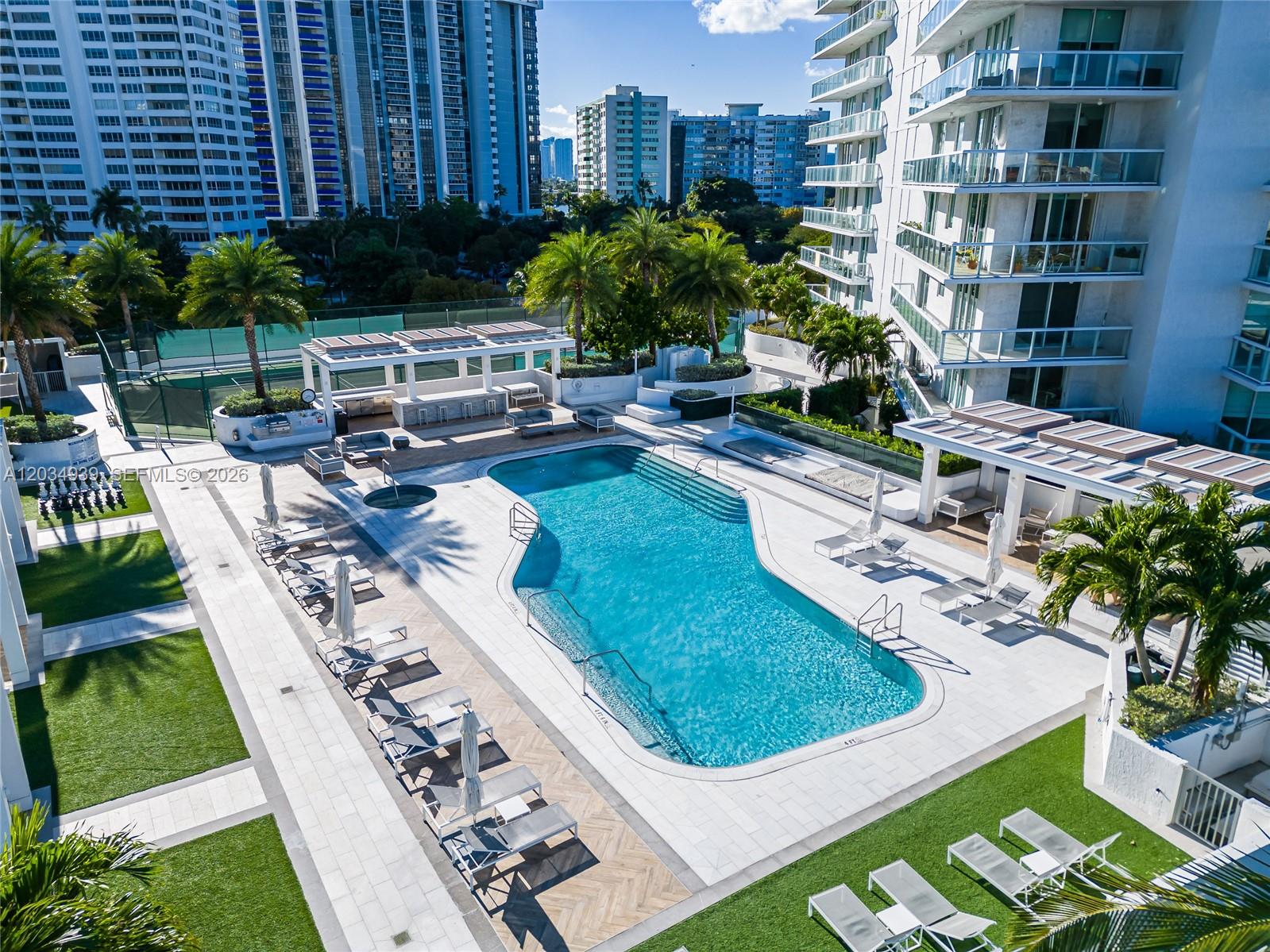 An outdoor swimming pool area features lounge chairs, palm trees, and a covered patio — 10 Venetian Way, Miami Beach FL 33139, MIAMI BEACH, FL