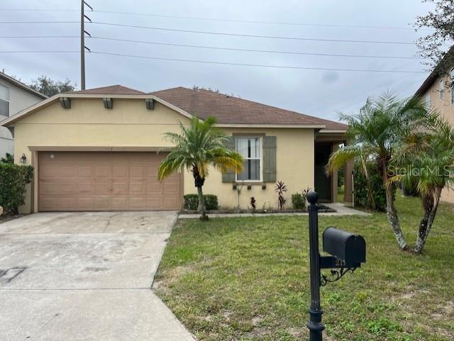 A single-story house with a tan stucco exterior, a brown roof, and a two-car garage — 217 SAND RIDGE DRIVE, DAVENPORT, FL