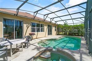 A screened-in patio features a swimming pool, a hot tub, and a dining table — 217 SAND RIDGE DRIVE, DAVENPORT, FL