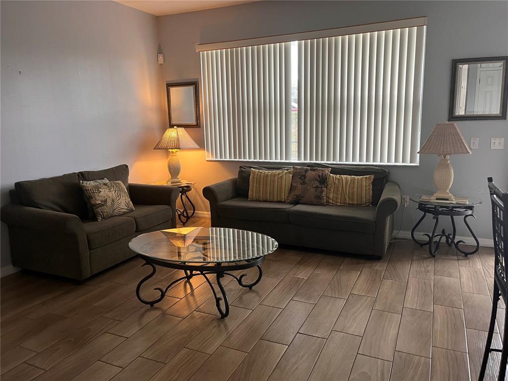 A living room features two dark sofas, a glass coffee table, and wood-look tile flooring — 217 SAND RIDGE DRIVE, DAVENPORT, FL