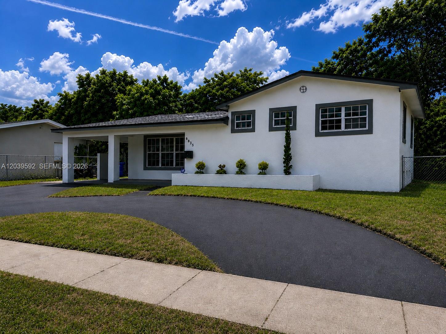 A white single-story house features a dark gray roof, a curved driveway, and a front lawn — 18935 NW 8th Ave, Miami Gardens FL 33169, MIAMI GARDENS, FL