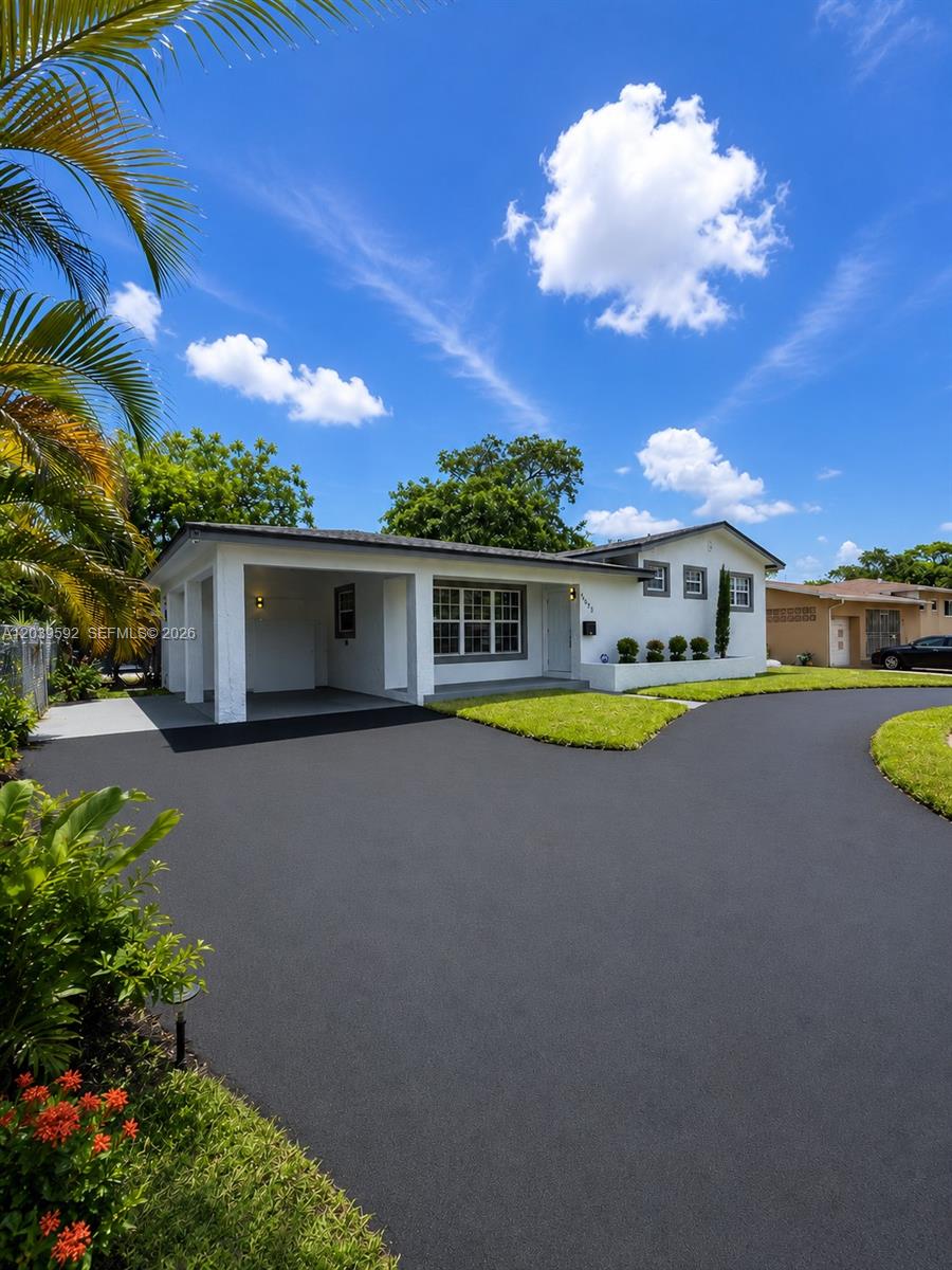 A white single-story house with a carport and a large, freshly paved asphalt driveway — 18935 NW 8th Ave, Miami Gardens FL 33169, MIAMI GARDENS, FL