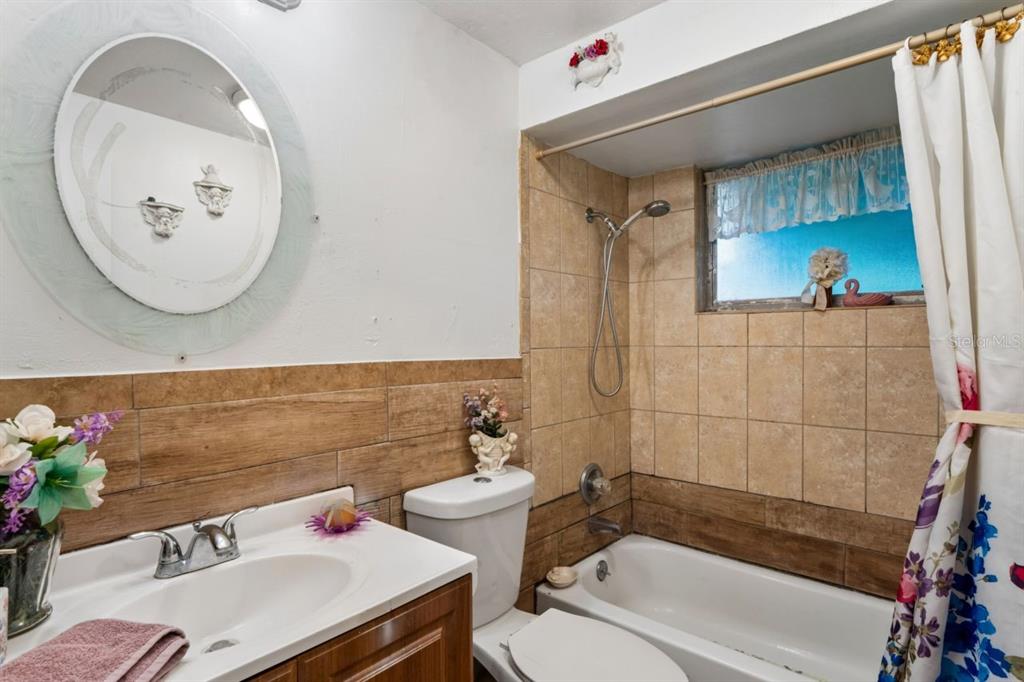 A bathroom features a vanity, toilet, and a tiled bathtub-shower combination with a window — 3415 CLYDESDALE DR unit 5, HOLIDAY, FL