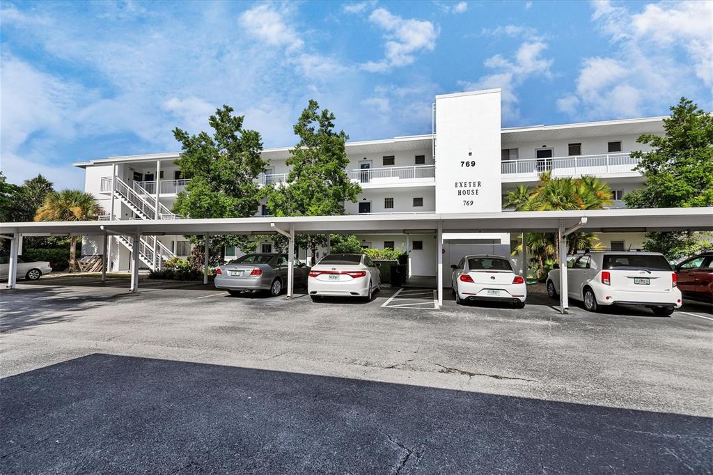 A multi-story apartment building features a covered parking area with several parked cars — 769 JOHN RINGLING BOULEVARD UNIT 36EXET, SARASOTA, FL