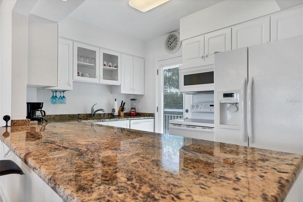 A kitchen features white cabinets, granite countertops, and a white refrigerator — 769 JOHN RINGLING BOULEVARD UNIT 36EXET, SARASOTA, FL