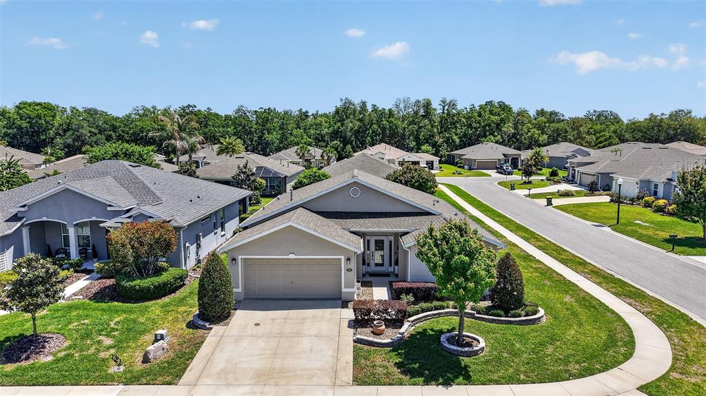 An aerial view shows a suburban house with a gray roof, garage, and landscaped yard — 4307 BENT CREEK LANE, LEESBURG, FL