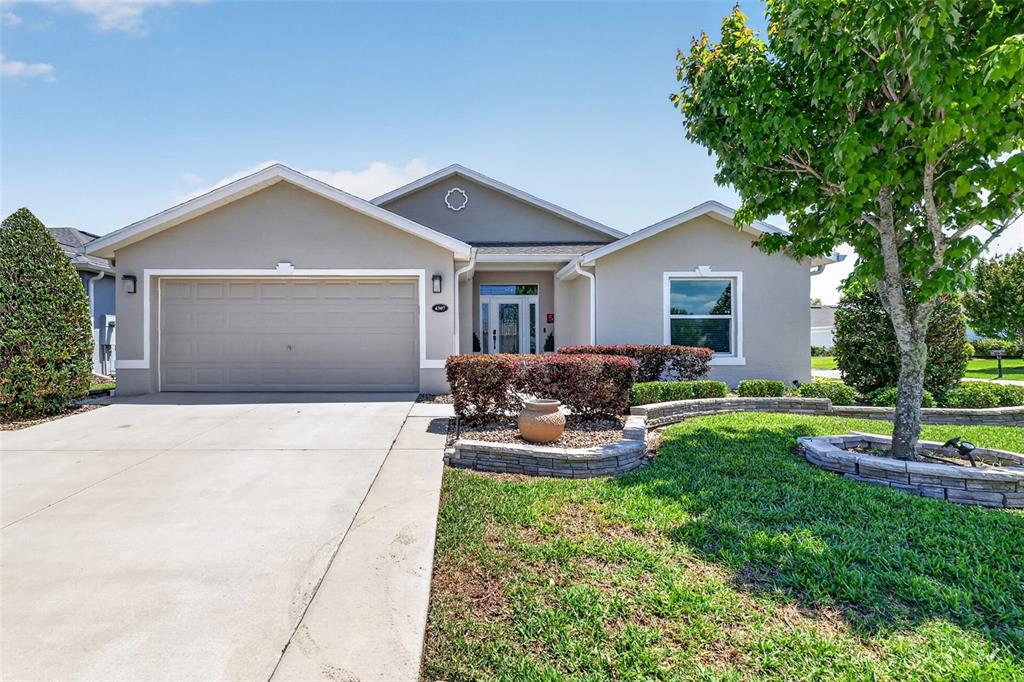A single-story house features a beige exterior, a two-car garage, and a landscaped front yard — 4307 BENT CREEK LANE, LEESBURG, FL