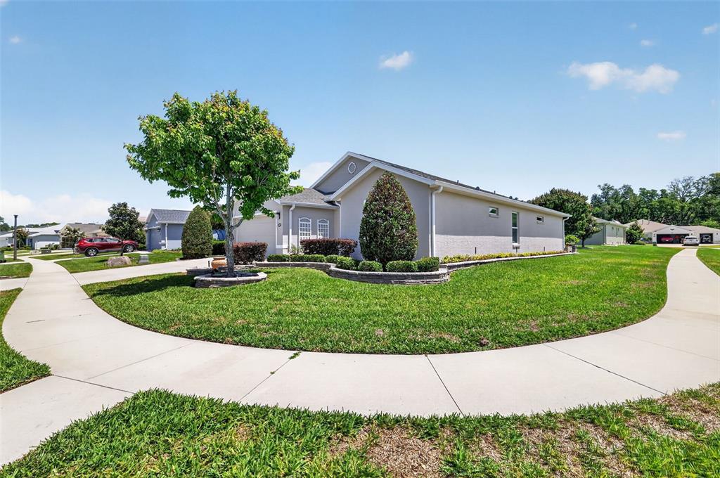 A single-story house with a beige exterior, a manicured lawn, and a curved concrete walkway — 4307 BENT CREEK LANE, LEESBURG, FL