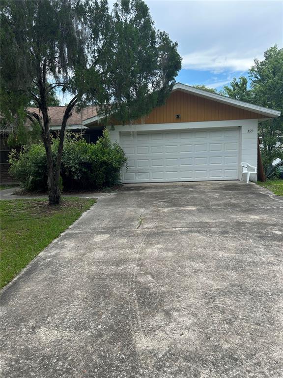 A single-story house with a white garage door, brown siding, and a concrete driveway — 305 VIOLETWOOD ROAD, DELAND, FL