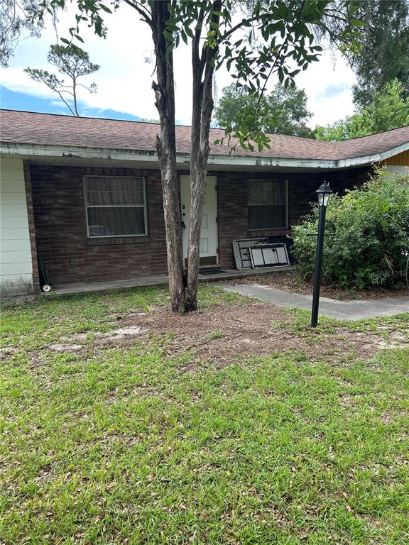 A single-story brick house with a front door, two windows, and a tree in front — 305 VIOLETWOOD ROAD, DELAND, FL