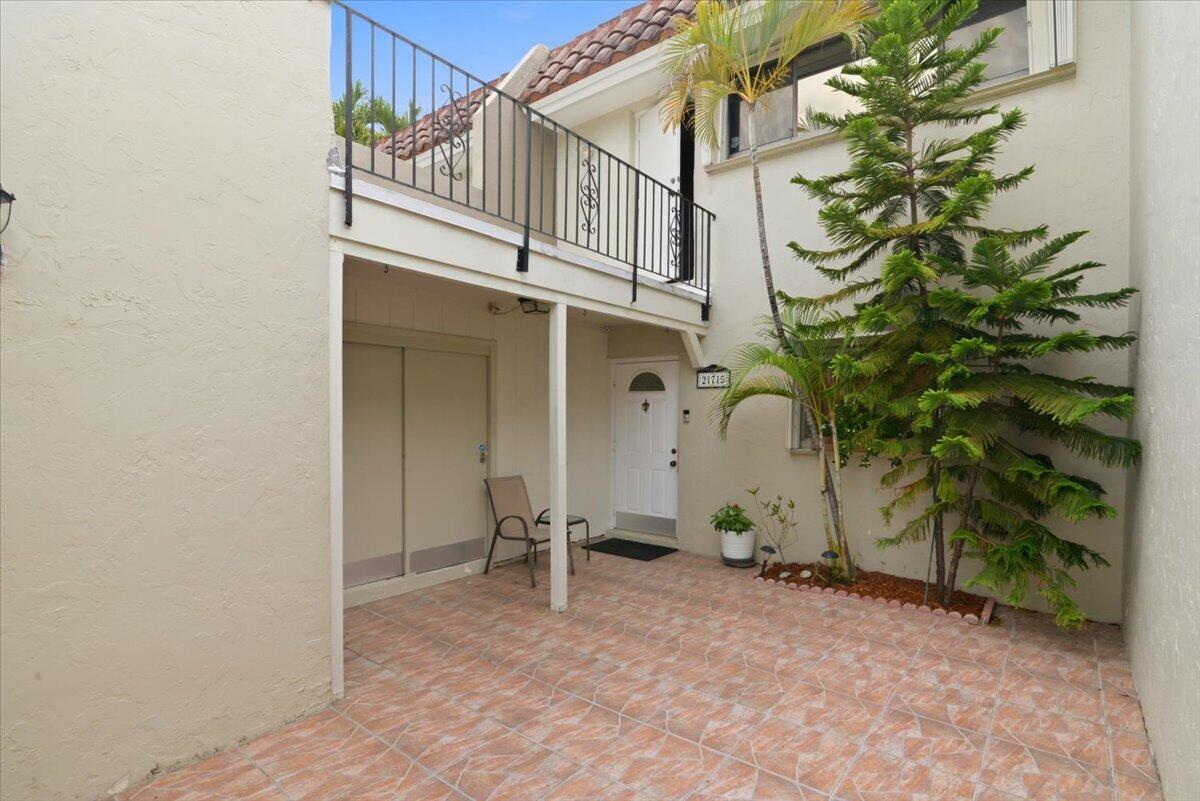 A tiled patio leads to a white front door beneath a second-story balcony — 275 Jacaranda Drive, Plantation FL 33324, PLANTATION, FL