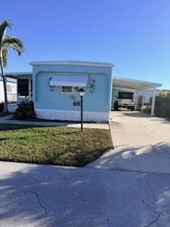 A light blue mobile home with a white awning and an attached carport — 102 N Warner Drive, Jensen Beach FL 34957, JENSEN BEACH, FL