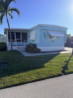 A light blue mobile home features a screened-in porch and a white metal awning — 102 N Warner Drive, Jensen Beach FL 34957, JENSEN BEACH, FL