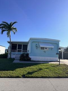 A light blue mobile home features a screened-in porch and a palm tree in the yard — 102 N Warner Drive, Jensen Beach FL 34957, JENSEN BEACH, FL