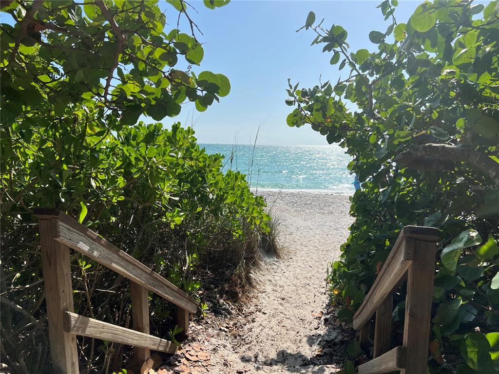 A sandy path leads through lush green foliage to a sunny beach and ocean view — 17122 ORIENT AVENUE, PORT CHARLOTTE, FL