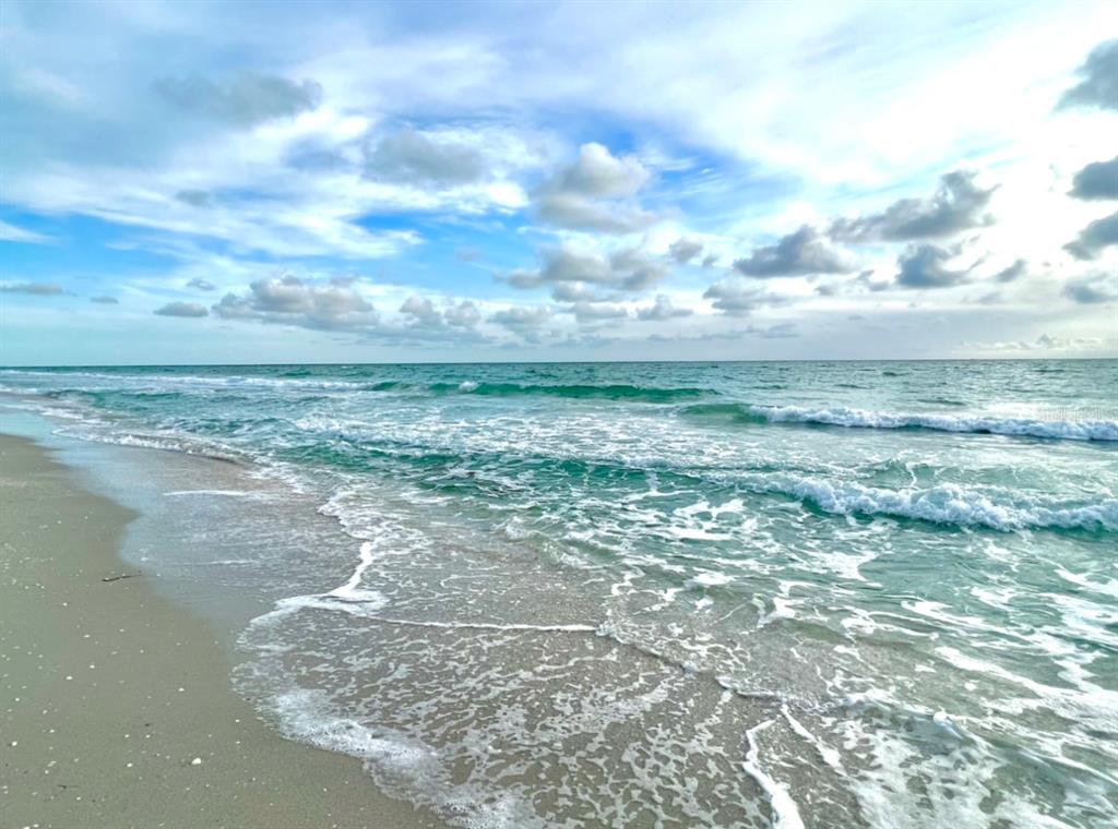 A sandy beach meets turquoise ocean waves under a cloudy blue sky — 17122 ORIENT AVENUE, PORT CHARLOTTE, FL