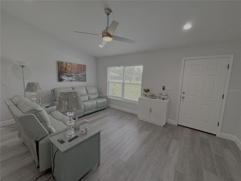 A living room features light gray flooring, a ceiling fan, a sofa, and a front door — 3722 SW 149TH TERRACE, OCALA, FL