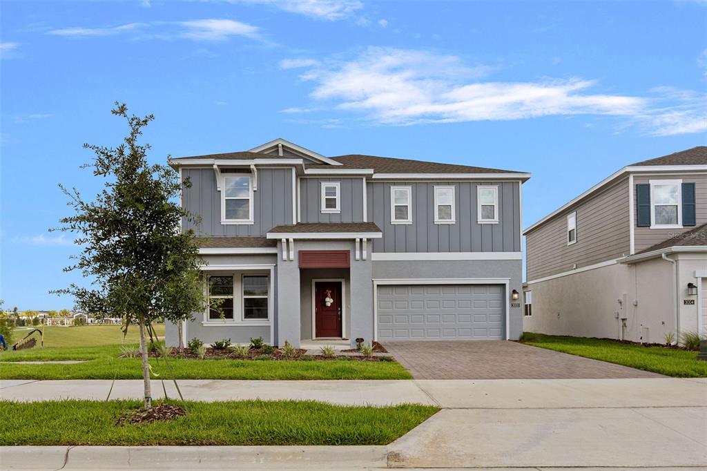 A two-story gray house with a red front door and a two-car garage — 3000 NAMASTE DRIVE, CLERMONT, FL