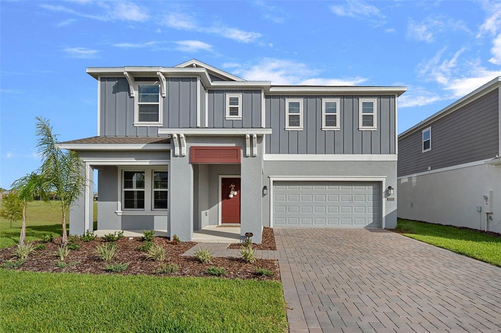 A two-story house with gray siding, a red front door, and a paved driveway — 3000 NAMASTE DRIVE, CLERMONT, FL