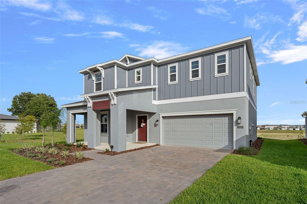 A two-story house with gray vertical siding, a stucco facade, and a two-car garage — 3000 NAMASTE DRIVE, CLERMONT, FL