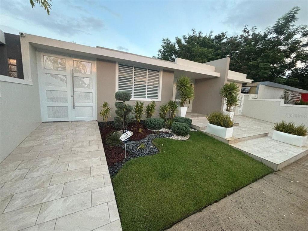 A modern house exterior features a tiled walkway, manicured lawn, and decorative landscaping — 59 REXVILLE DEVELOPMENT UNIT BM-26, BAYAMON, PR