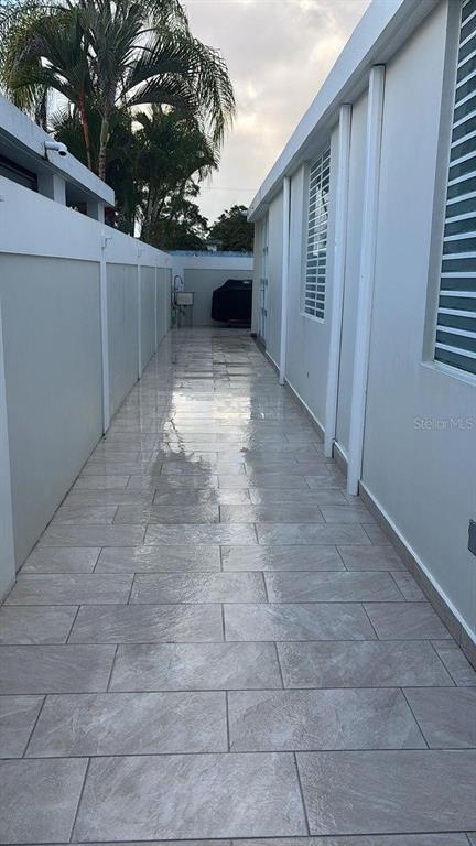 A narrow outdoor walkway features light-colored rectangular floor tiles between a white wall and fence — 59 REXVILLE DEVELOPMENT UNIT BM-26, BAYAMON, PR