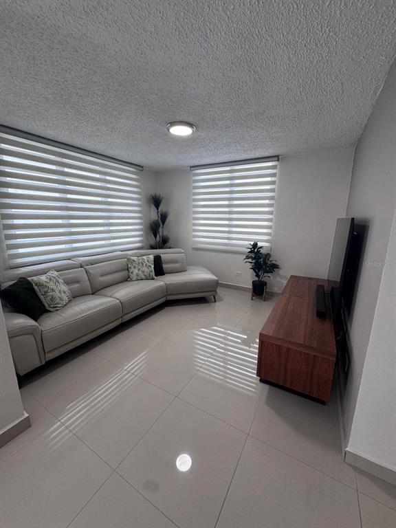 A living room features a light gray sectional sofa, a wooden media console, and tiled floors — 59 REXVILLE DEVELOPMENT UNIT BM-26, BAYAMON, PR