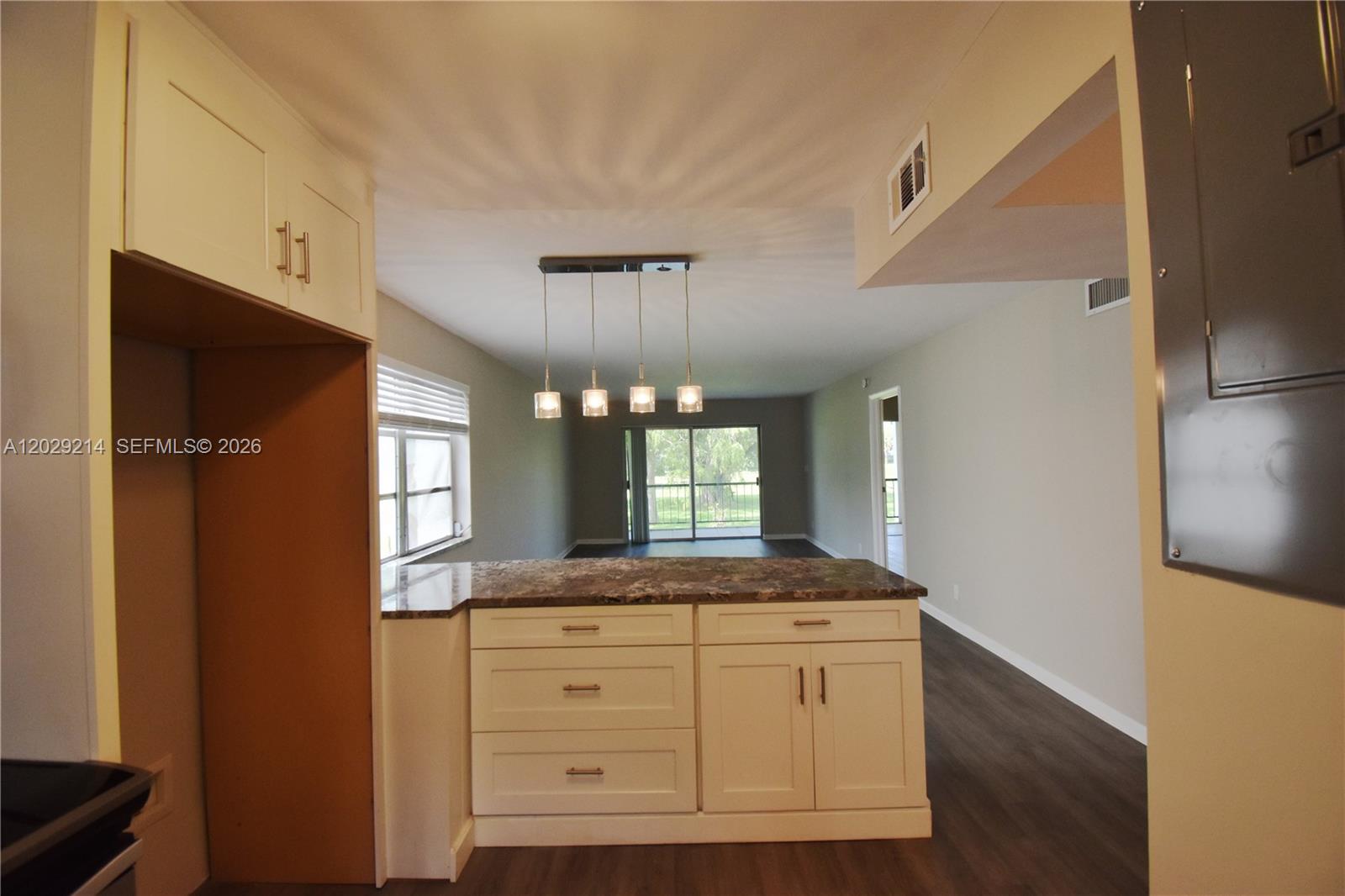 A kitchen island with a stone countertop sits in front of an open living area — 6080 NW 44th St # 201, Lauderhill FL 33319, LAUDERHILL, FL