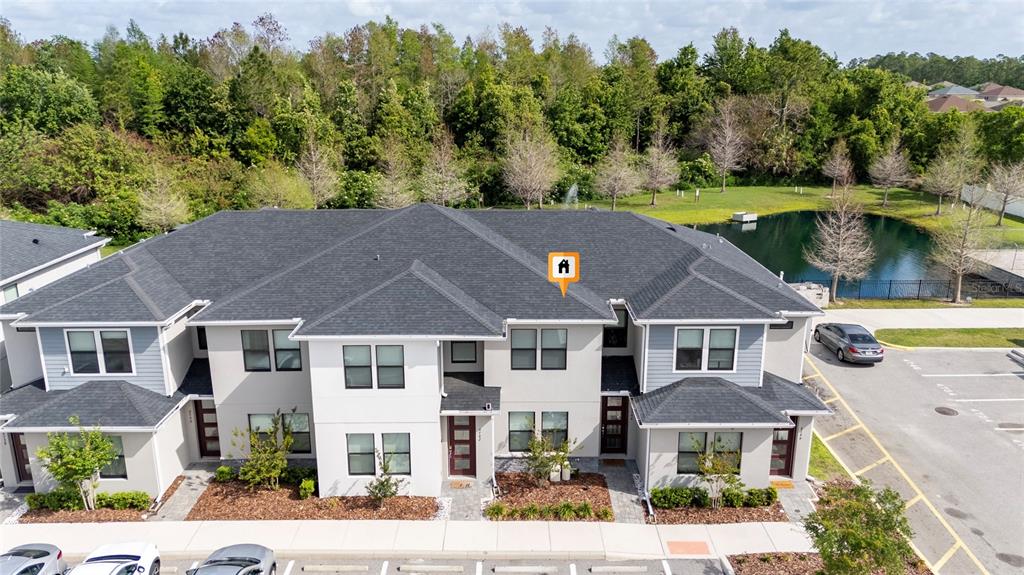 An aerial view shows a two-story townhouse building with a gray roof and pond — 4744 TERRA ESMERALDA DRIVE, KISSIMMEE, FL
