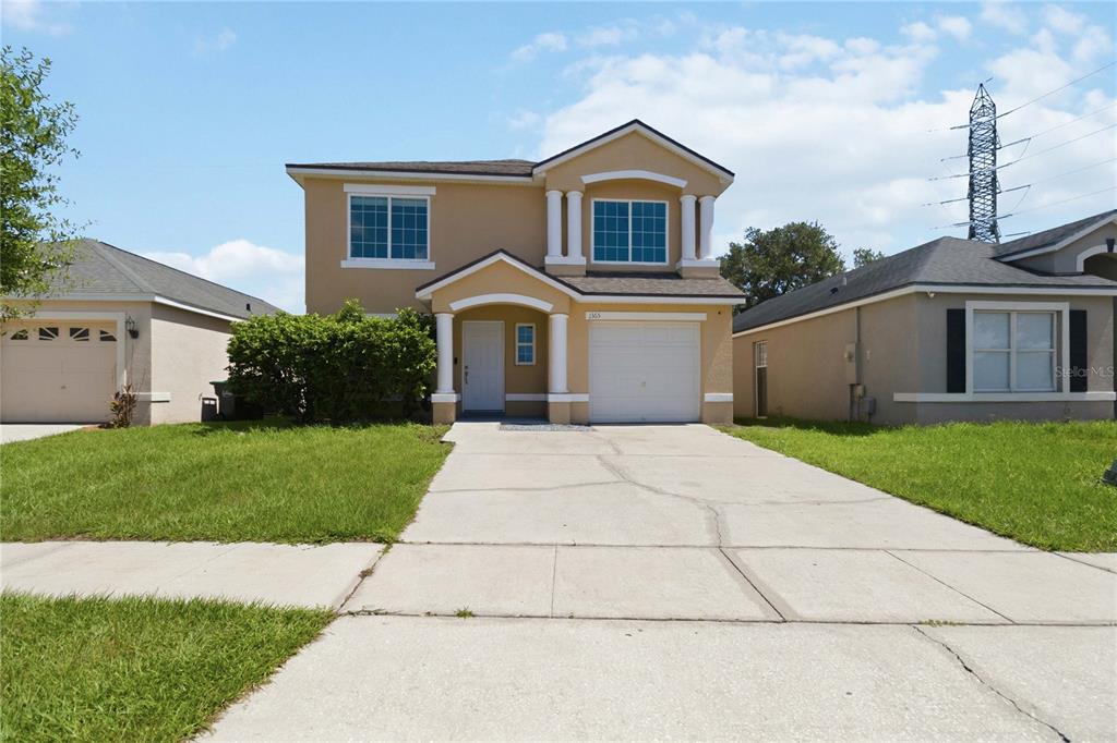 A two-story tan house with a white garage door and a concrete driveway — 1365 CAREY GLEN CIRCLE, ORLANDO, FL