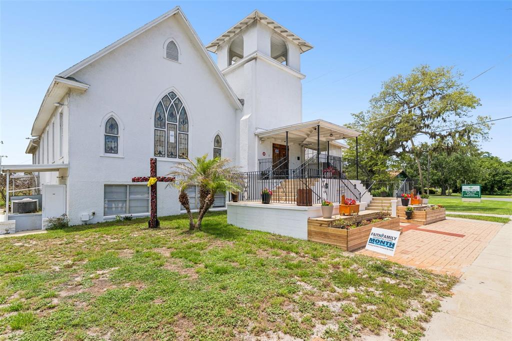 A white church building features a bell tower, arched windows, and a cross in front — 1050 DAYTONA AVENUE, DAYTONA BEACH, FL