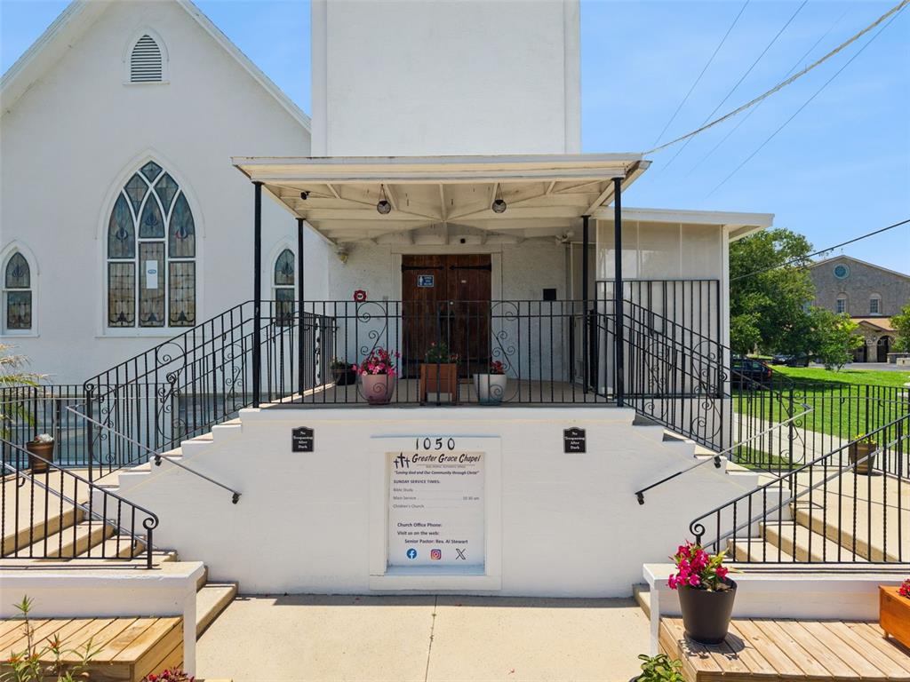 The exterior of a white church building features a covered entrance with stairs and railings — 1050 DAYTONA AVENUE, DAYTONA BEACH, FL