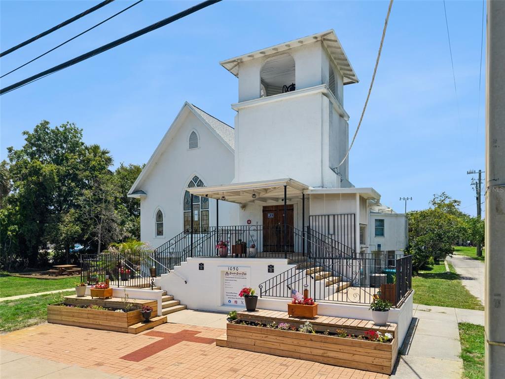 A white church building features a bell tower, front steps, and wooden planter boxes — 1050 DAYTONA AVENUE, DAYTONA BEACH, FL