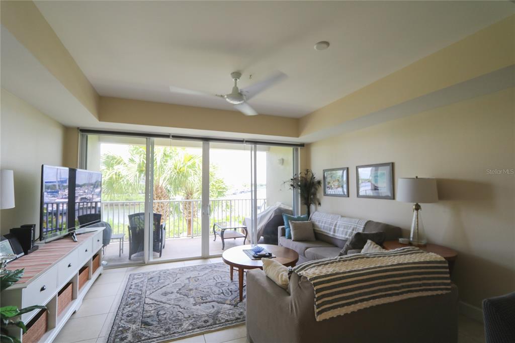 A living room features a sofa, television, area rug, and a balcony with water views — 447 BAHIA BEACH BOULEVARD, RUSKIN, FL