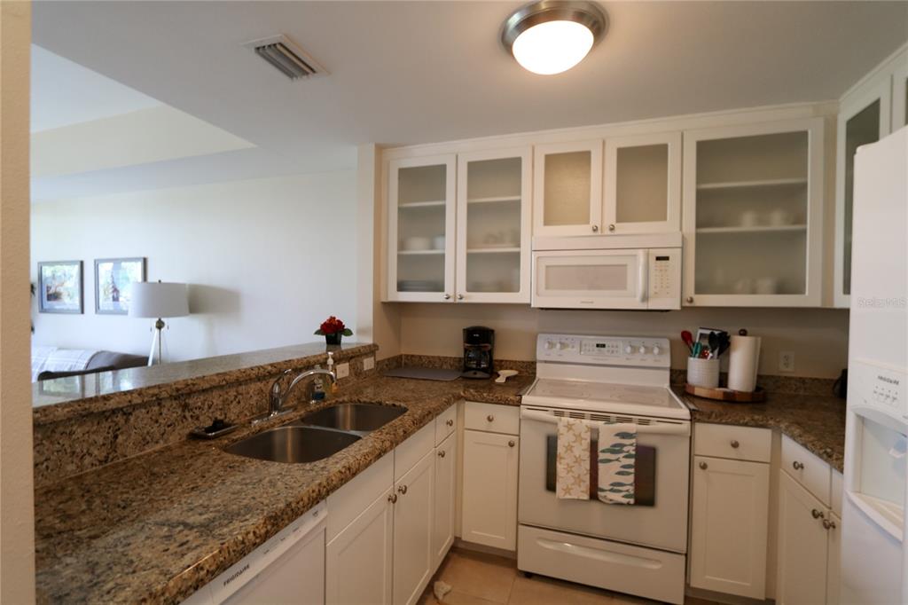 A kitchen features white cabinets, granite countertops, a white stove, and a double sink — 447 BAHIA BEACH BOULEVARD, RUSKIN, FL