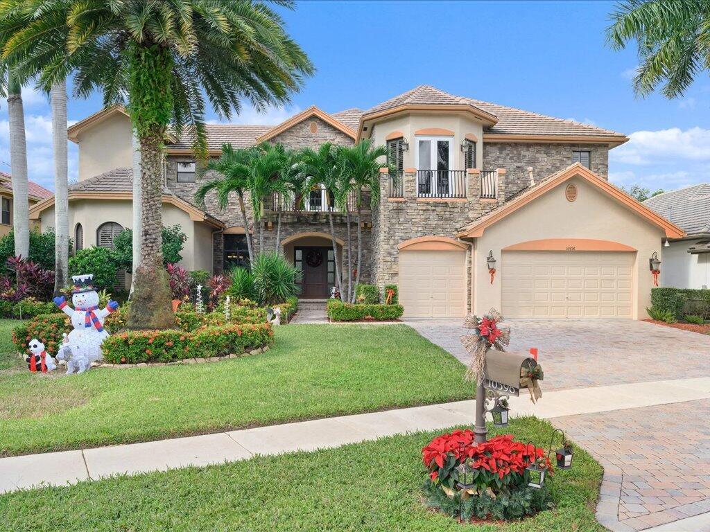 A two-story stone and stucco house with a three-car garage and a landscaped front yard — 10596 Versailles Boulevard, Wellington FL 33449, WELLINGTON, FL
